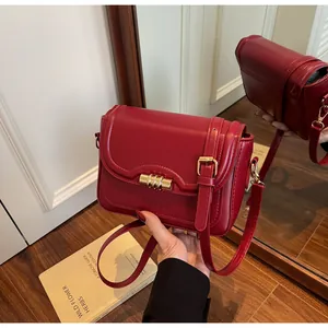 Detail of red PU leather bag with golden cylindrical lock and strap embellishment