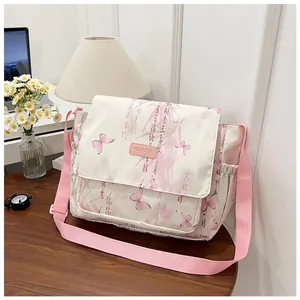 Detail of white canvas crossbody bag with pink butterfly prints and wide fabric strap