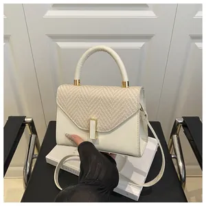 Detail of cream white Kelly bag with straw texture flap and gold lock closure