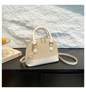 Close-up of beige straw shell bag with white leather trim and gold hardware details