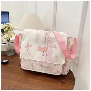 Close-up of white messenger bag with pink butterfly print and woven shoulder strap