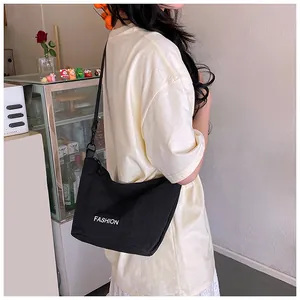Close-up of minimalist black nylon crossbody bag with white FASHION lettering