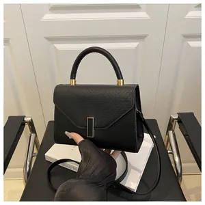 Detail of black leather handbag featuring lychee texture and golden metal buckle