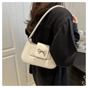 Détail du sac en similicuir blanc crème avec fermoir nœud en métal et bandoulière chic
