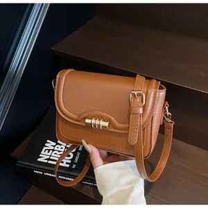 Detail of caramel PU leather crossbody bag with elegant gold coil spring metal buckle