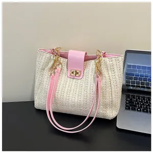 Détail du sac cabas en paille tressée avec lanière en cuir rose et fermoir doré en métal