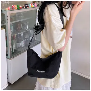 Detail of a black nylon crossbody moon bag with white Fashion text and wide shoulder strap