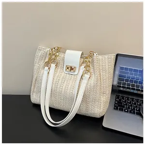 Détail du sac cabas en paille avec garniture en cuir blanc et fermoir doré chic