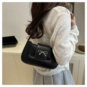 Détail du sac baguette noir élégant avec une boucle en métal dorée en forme de nœud