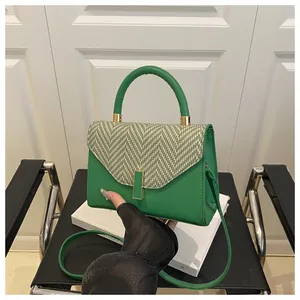 Detail of green kelly bag with herringbone pattern flap on a black chair