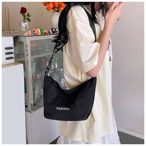 Detail view of black nylon crescent shoulder bag with white Fashion text and zipper close