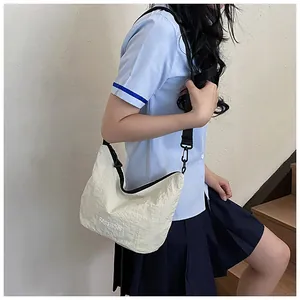 Detailed view of beige crescent bag with fashion embroidery on model in school uniform