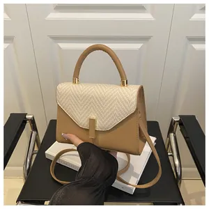 Detail of contrast stitch handbag with brown leather trim and woven fabric flap texture