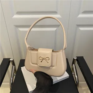 Sac baguette beige chic avec boucle nœud dorée et bandoulière en cuir minimaliste