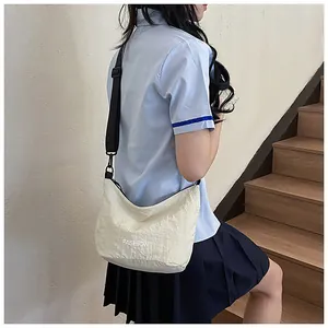 Detail of off-white pleated dumpling bag showing the fashion logo and black nylon strap