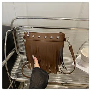 Dettaglio della borsa a tracolla in pelle PU marrone con rivetti argento e nappe