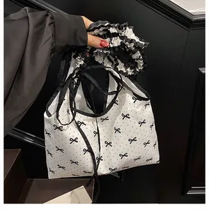 Detail of white canvas bag with black polka dots, bow print and ruffled striped edge