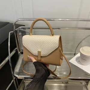 Chic two-tone Kelly bag with straw flap and leather body displayed on a metal shelf