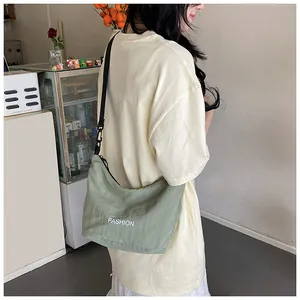 Detail view of light green casual dumpling bag with FASHION print on model's back