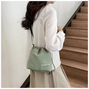 Close-up of green nylon bucket bag with drawstring closure and fashion text print