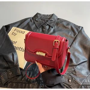 Detail of red PU leather shoulder bag featuring a gold metal buckle and vertical strap