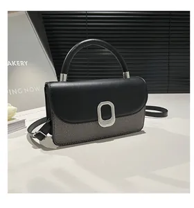Detail of a color-block patchwork handbag with silver oval buckle and mixed fabric texture