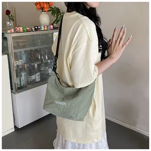Sage green croissant bag with FASHION logo and adjustable strap shown on model