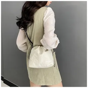Detail of cream nylon bucket bag featuring drawstring closure and fashion letter print
