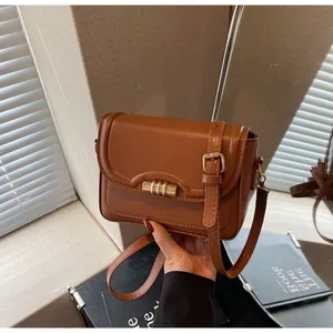 Detail of caramel brown leather crossbody bag featuring wave stitching and gold hardware