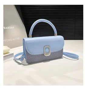 Detail of light blue crossbody bag with silver oval buckle and patchwork texture