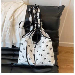 Detail of ruffled shoulder strap and black bow print on white canvas tote bag