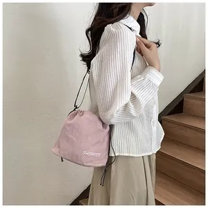 Detail of light pink drawstring bucket bag with fashion print and black shoulder strap