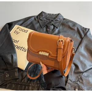 Detail of a brown PU leather shoulder bag with a cylindrical gold buckle and adjustable strap