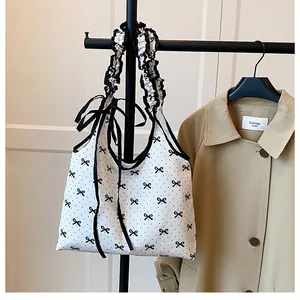 Close-up of pleated shoulder bag handle with polka dots and black ribbon bow detail