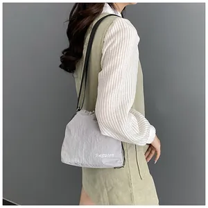 Detail of light grey nylon drawstring crossbody bag worn over shoulder by a model