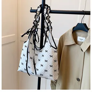 Detail of white canvas tote bag with black polka dots, bow print and ruffled shoulder strap