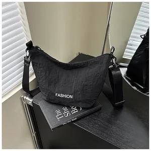 Detail of black wrinkled nylon crescent bag with white Fashion text and adjustable strap