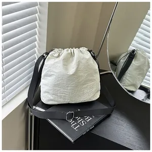 Detail of cream nylon drawstring bucket bag with black strap and fashion logo