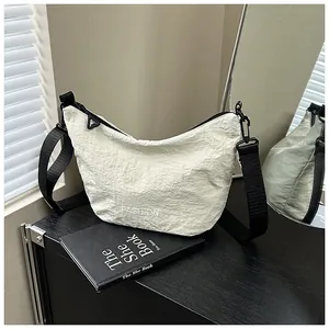 Detail of off-white pleated crescent bag with black strap reflected in a mirror