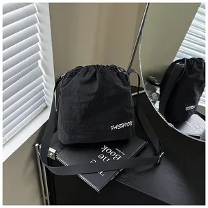 Detailed view of black nylon drawstring bucket bag featuring white Fashion lettering