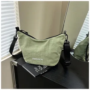 Detail of light green nylon dumpling bag showing the metal zipper and wide black strap