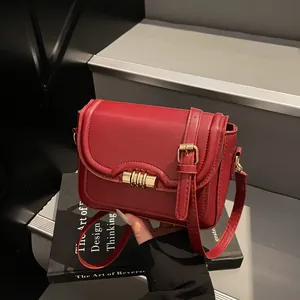 Chic dark red PU leather crossbody bag with gold buckle on minimalist stairs