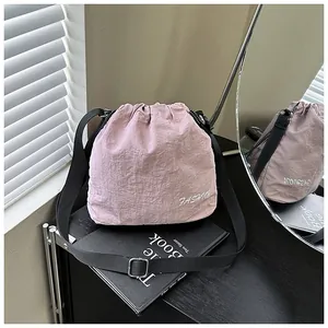 Detail of pink nylon bucket bag with FASHION embroidery and black adjustable strap