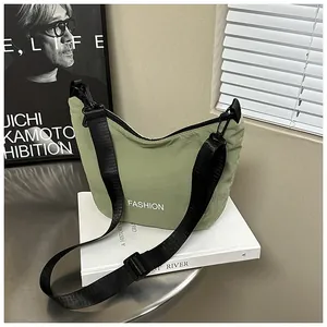 Detail of green half-moon crossbody bag with white fashion print and wide nylon strap