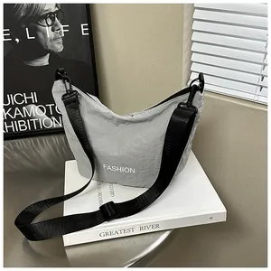 Detail of light grey nylon dumpling bag with adjustable black strap on minimalist background