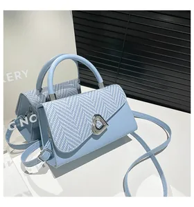 Detail of light blue woven flap handbag with heart-shaped silver rotating clasp closure