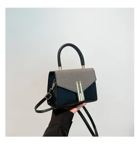 Detail of contrast stitch handbag featuring grey tweed fabric and gold buckle accents