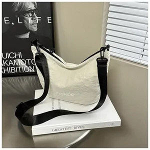 Detail of light beige pleated nylon crossbody bag with white FASHION text and black strap