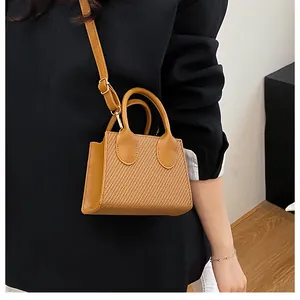 Brown woven texture crossbody bag with adjustable strap worn by a model in a black suit