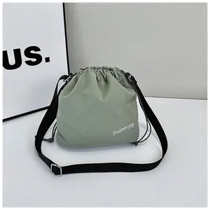 Close-up of light green nylon bucket bag with adjustable black strap and fashion print